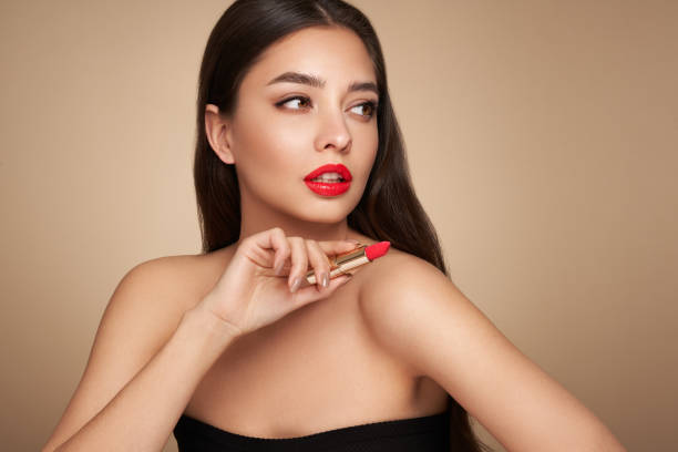 A beautiful young woman applying lipstick