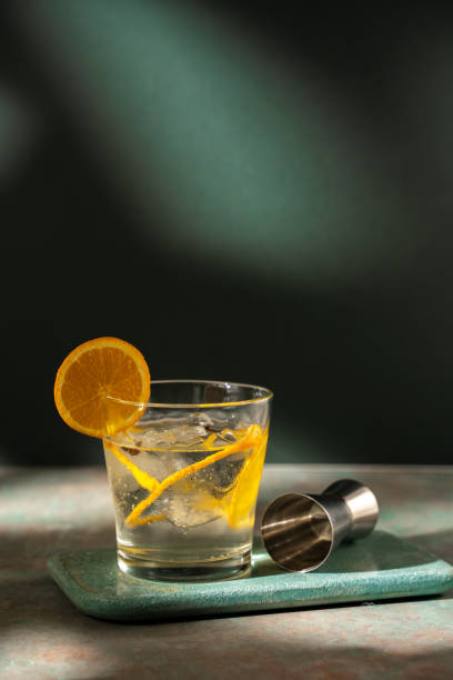 Glass of gin tonic with orange slice and ice. dark green background Glass of gin tonic with orange slice and ice, on a stone table and dark green background club soda stock pictures, royalty-free photos & images