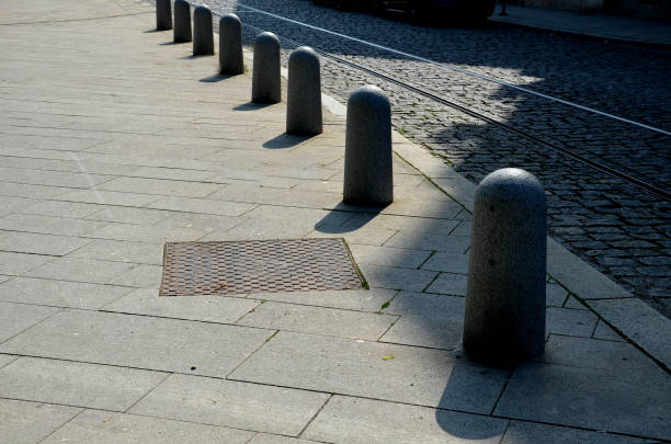 istock stone barriers in a square shaped cylinder with a hemisphere on top. granite curbs as stops at the parking lot. chain decorative fence against a colony of pedestrians and vehicles with a metal bollard 1404630301