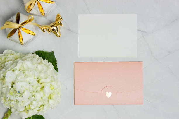 istock White hydrangea with pink envelope and letter on marble background. 1404631572