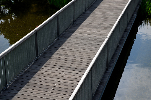 metal galvanized railing on the bridge. The filling is formed by a metal mesh of expanded metal. transparent railing better view of the river pond water