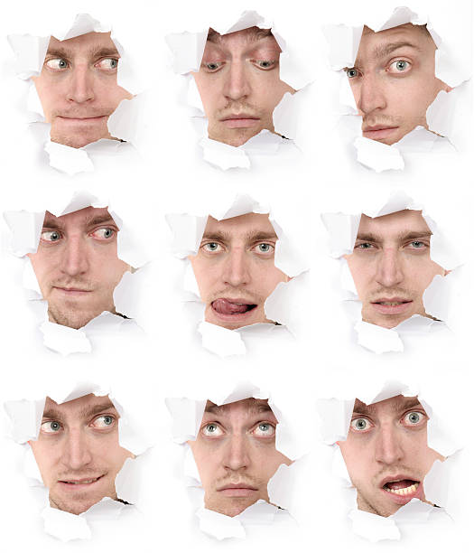 expressive faces of the emotional person in a paper hole stock photo