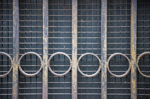 Rusty metallic security bars on window, pattern with circles between, grid behind, full frame, backgrounds