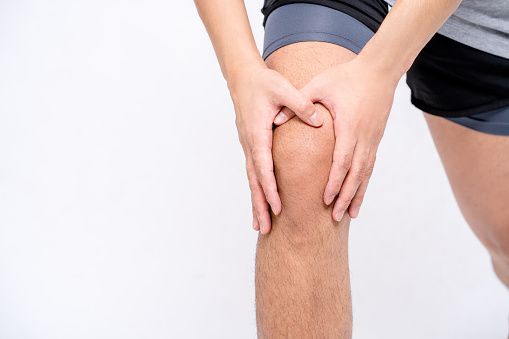 Young man had joint pain from arthritis and tendon problems. He touches knees at pain points, isolated on white background.