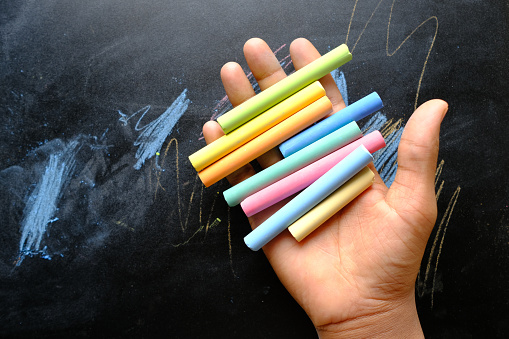 Large group of multi colored pencils shot from above on blackboard background. The pencils are coming from the bottom-right corner leaving useful copy space for text and/or logo at the center. High resolution 42Mp studio digital capture taken with Sony A7rII and Sony FE 90mm f2.8 macro G OSS lens