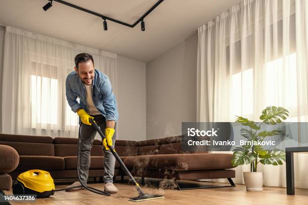 Young Man Using Vacuum Cleaner At Home Stock Photo - Download Image Now - Steam, Cleaner, Cleaning
