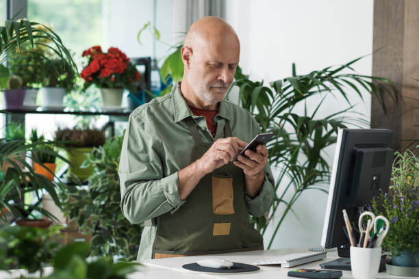 Professional florist taking orders on his smartphone stock photo