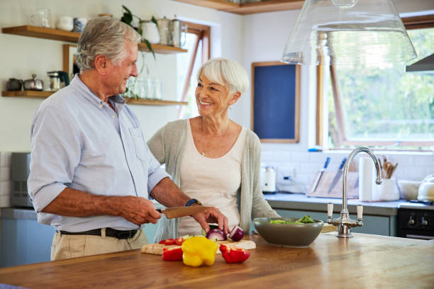 istock Senior couple smiling while preparing a lunch together in their kitchen 1404639366