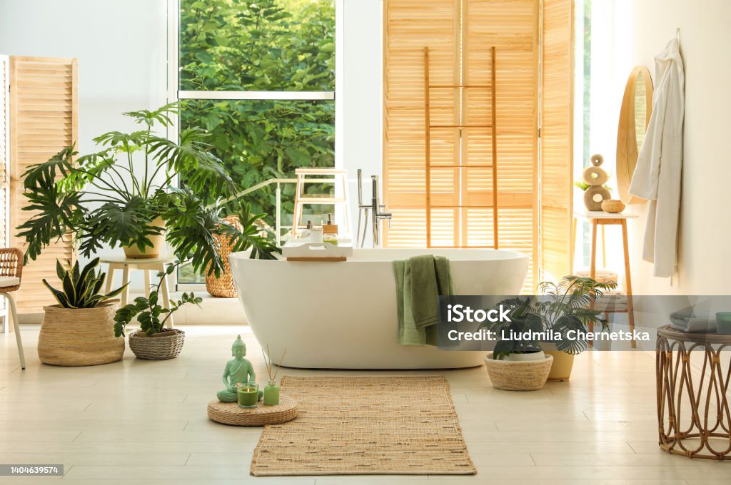Stylish bathroom interior with modern tub, window and beautiful houseplants. Home design Arrangement Stock Photo