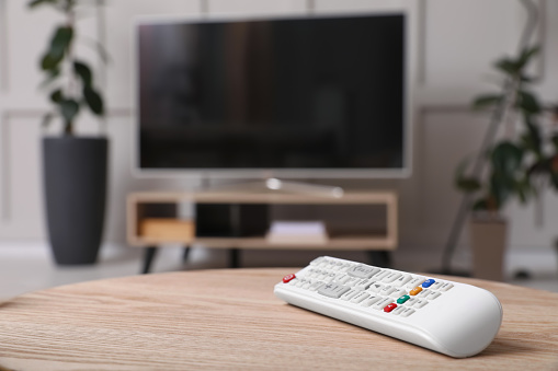 Wooden cabinet with modern TV indoors, focus on remote control