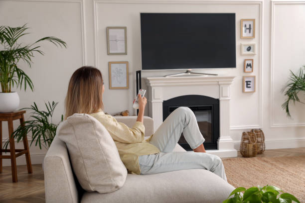 jovem assistindo televisão em casa. interior da sala com tv na lareira - changing channels - fotografias e filmes do acervo