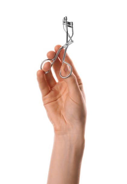 istock Woman holding eyelash curler on white background, closeup. Makeup tool 1404642282