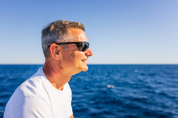 Crew member enjoying sitting on sailboat bow.