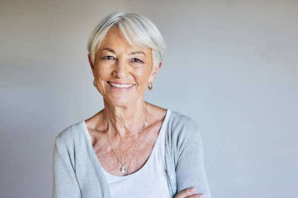 istock Senior woman smiling while standing against a gray wall at home 1404643395