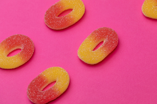 Extreme close up shot of gummy candies on a bright pink background