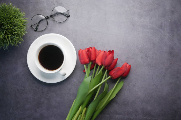 istock flat composition coffee, tulip flower and eyeglass on black background . 1404644857