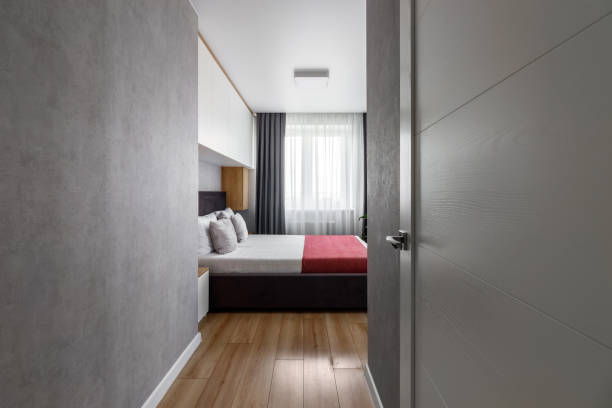 istock Bedroom with a bed tucked into a red bedspread and gray pillows 1404644963