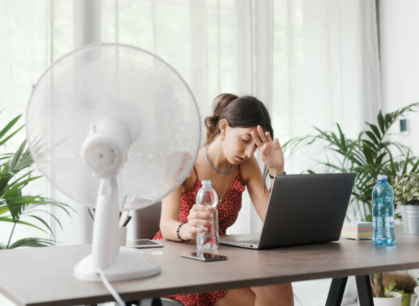 istock Woman cooling herself with an electric fan 1404646006