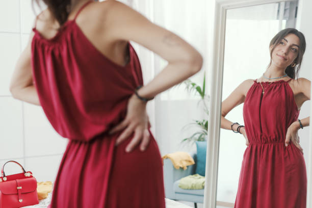 Elegant woman trying a new outfit Confident woman trying a new outfit and getting ready to go out, she is looking at herself in a mirror women satisfaction decisions cheerful stock pictures, royalty-free photos & images