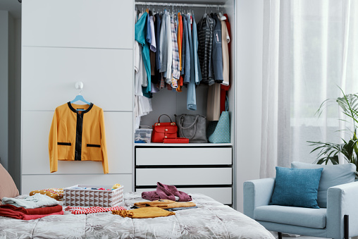 Collection of clothes in the closet and on the bed, bedroom interior
