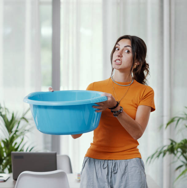 Woman collecting water leaking from the ceiling stock photo