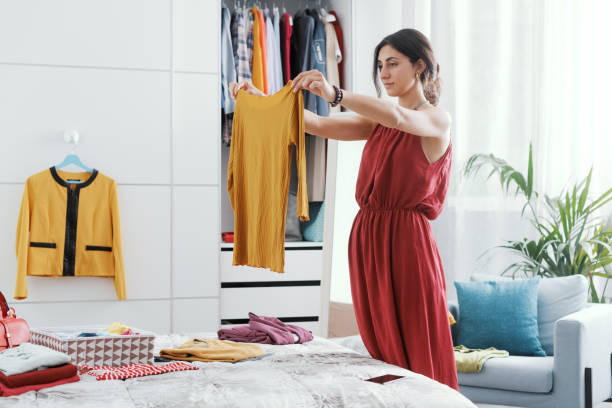 Woman choosing clothes in her bedroom stock photo