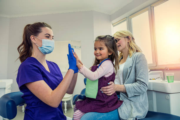 mom brought her little daughter to the dentist's office to treat baby teeth. stock photo