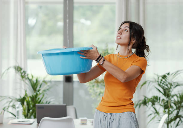 istock Woman collecting water leaking from the ceiling 1404648626