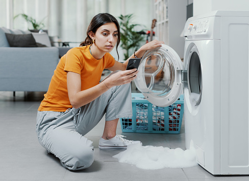 Worried woman calling a repairman, the washing machine is broken