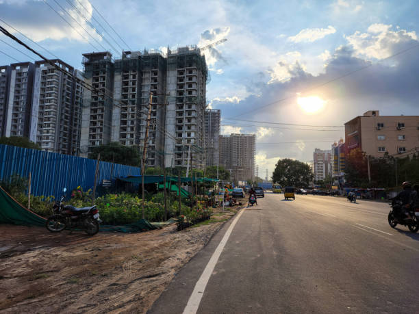 Picture of Indian cityscape. newly build tall residencial buildings and apartments, people riding vehicles of road, bright sunlight with blue sky and clouds on background. stock photo