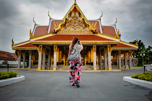 Selective focus. Young woman walking through the streets of thailand. Tourist taking a photo at a temple in Thailand