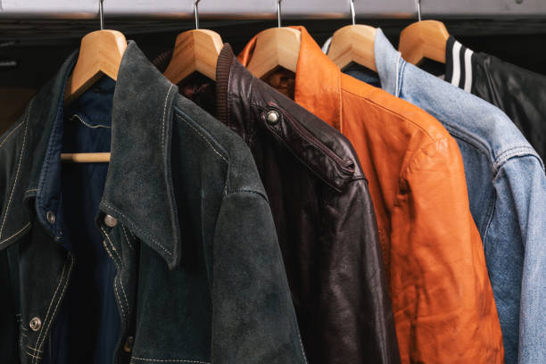 Various vintage jackets on clothing rack in second hand store Various vintage suede leather and jeans jackets on hanger rack in a used goods store. Thrifting and sustainability in clothing concept mens fashion stock pictures, royalty-free photos & images