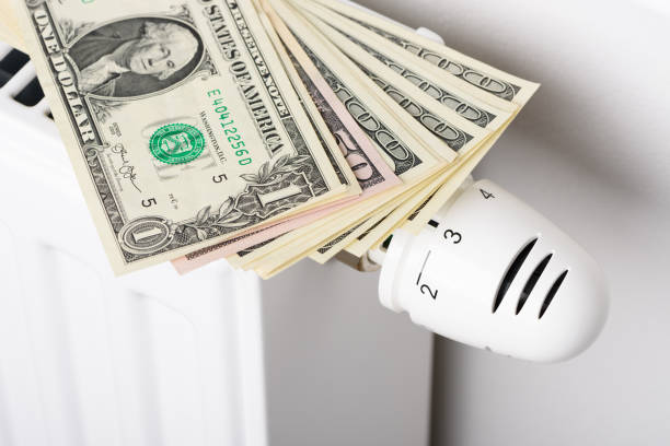 istock Stack of dollar banknotes on heating radiator battery with thermostat temperature regulator 1404655685