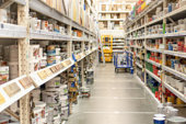 Aisle and racks with building and finishing materials in hardware store. View of hypermarket rows with paints, varnish and impregnation for wood. Blurred shopping and trading background.