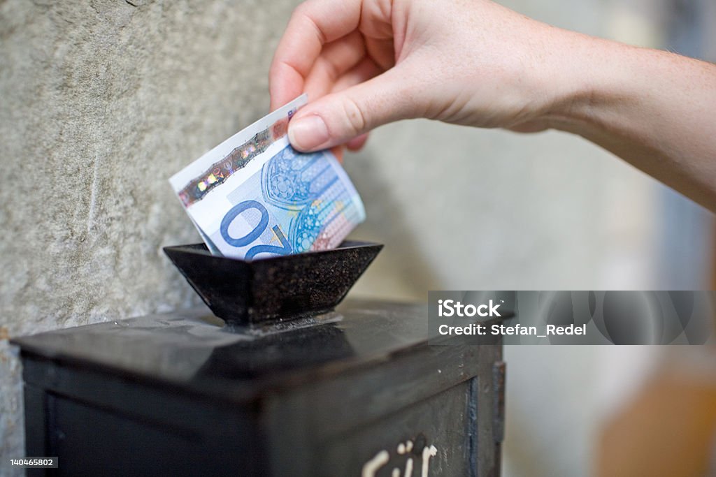 Offertory box in church Close-up: Inserting a banknote into offertory box. Very small DOF. Church Stock Photo