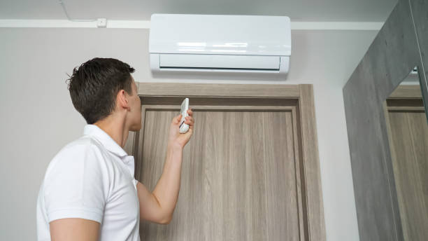 istock Man turns on air conditioner with remote control in hot room 1404658545