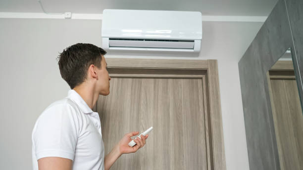 istock Man turns on air conditioner with remote control in hot room. 1404658551