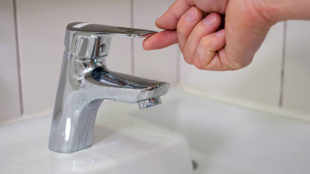 istock Male hands turn on water faucet and water quickly flows 1404658585