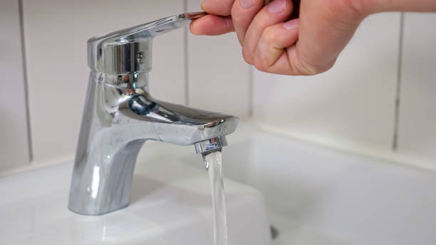 istock Male hands turn on water faucet and water quickly flows 1404658635
