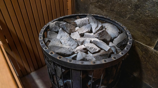 Close-up of sauna stove covered with stones on which water is thrown in order to produce steam. Electric sauna heater with stones in the sauna.
