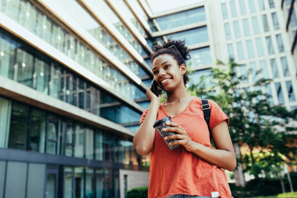 istock Young African American woman with sunglasses  using smart phone and talking 1404660256