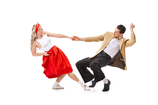 Expressive couple of dancers in vintage retro style outfits dancing social dance isolated on white background. Timeless traditions, 60s ,70s american fashion style. Dancers look excited