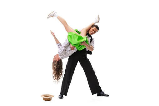 Dynamic portrait of dancing couple in vintage style clothes dancing, jumping isolated on white background. Concept of art, music, 60s ,70s american fashion style. Emotions, expressions