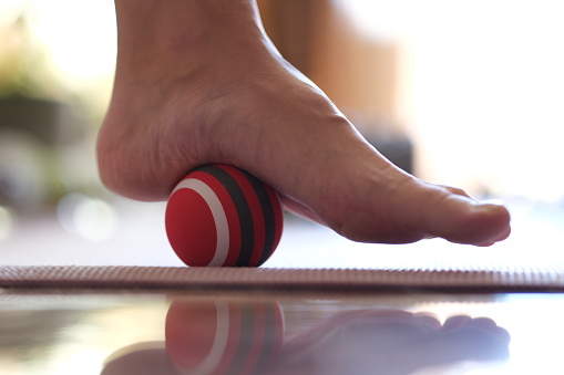 Foot massager and trigger massage ball closeup. Myofascial relaxation of the hypermobile muscles of the foot with a massage ball on a gymnastic mat