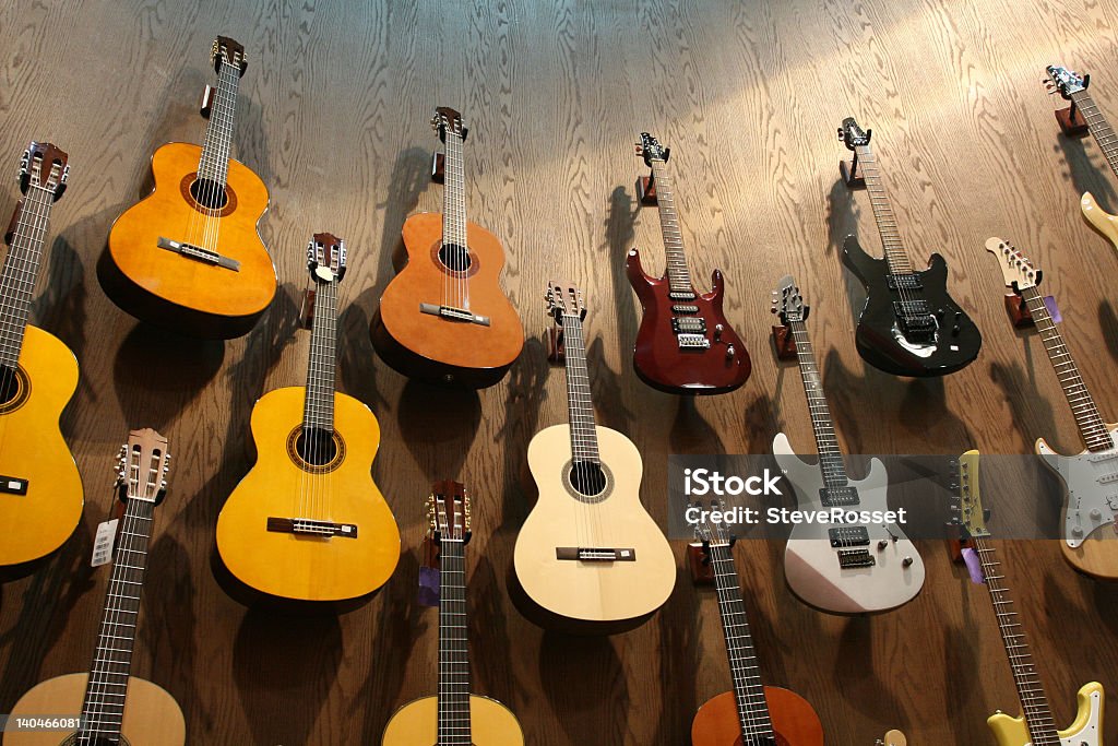 A wall of acoustic, classical, and electric guitars Guitar collection hanging from a music shop. Guitar Stock Photo