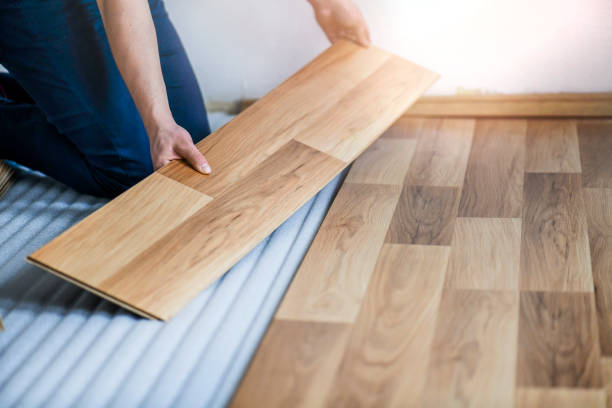 istock Worker hands installing timber laminate floor in modern house. Wooden floors renovation 1404662038
