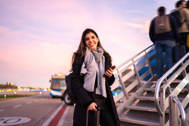 porträt einer frau, die im flugzeug einsteigt - airport lounge airport one person bag stock-fotos und bilder