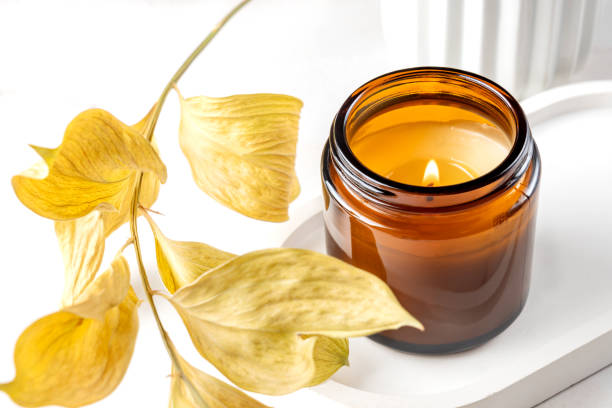 istock Stylish tender composition with burning candle and dry plants on whitemarble table against light background, space for text. Cozy interior element 1404663717