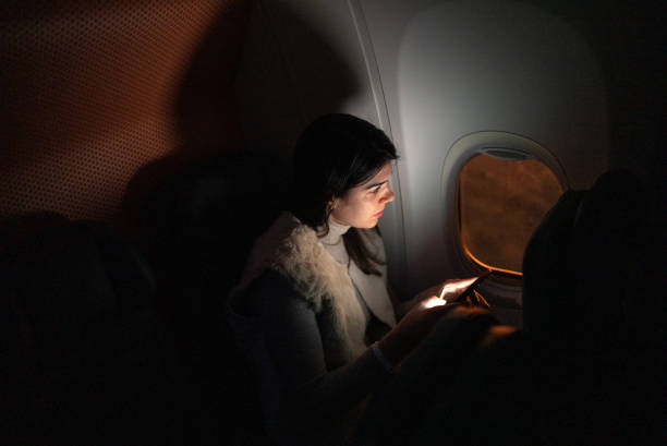 istock Woman traveling by plane and looking through window and using mobile phone 1404663899