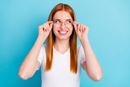 Photo of young attractive girl happy positive smile hands touch glasses look empty space isolated over blue color background.